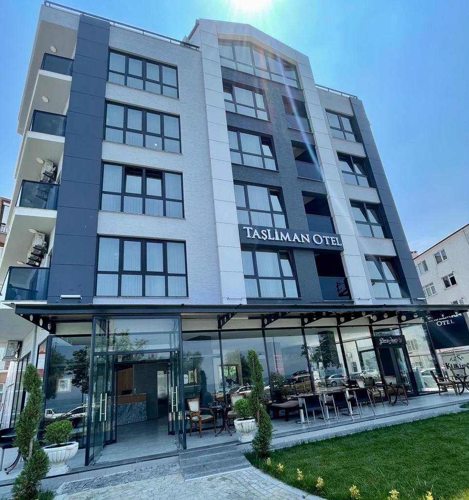 Taşliman Otel binasının cephesi; zemin katta camlı lobi ve bahçe