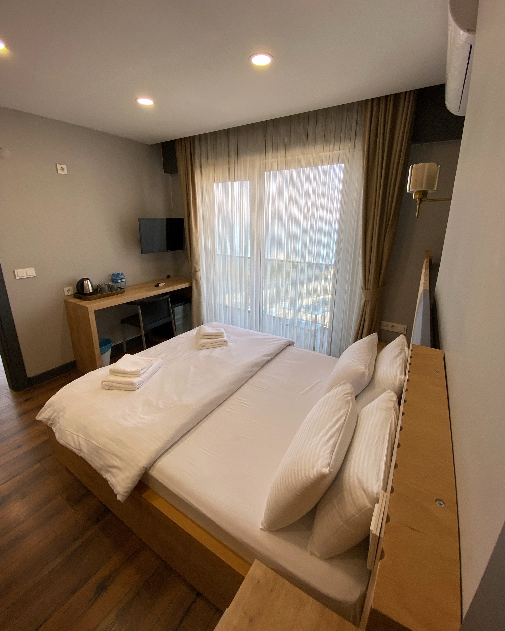 Çift kişilik yatak, çalışma masası ve balkon kapısıyla otel odası