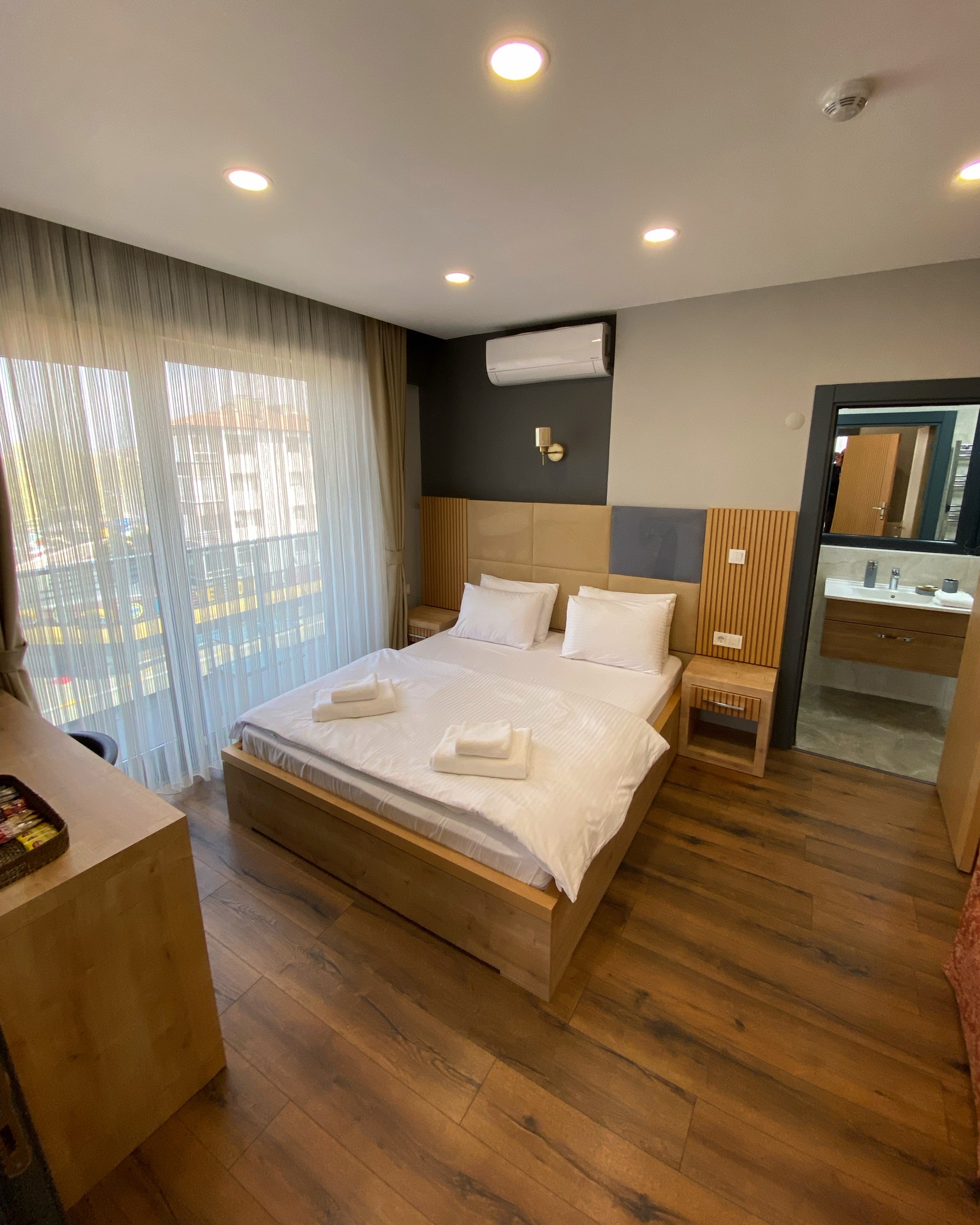 Ahşap zeminli, banyolu otel odası ve çift kişilik yatak